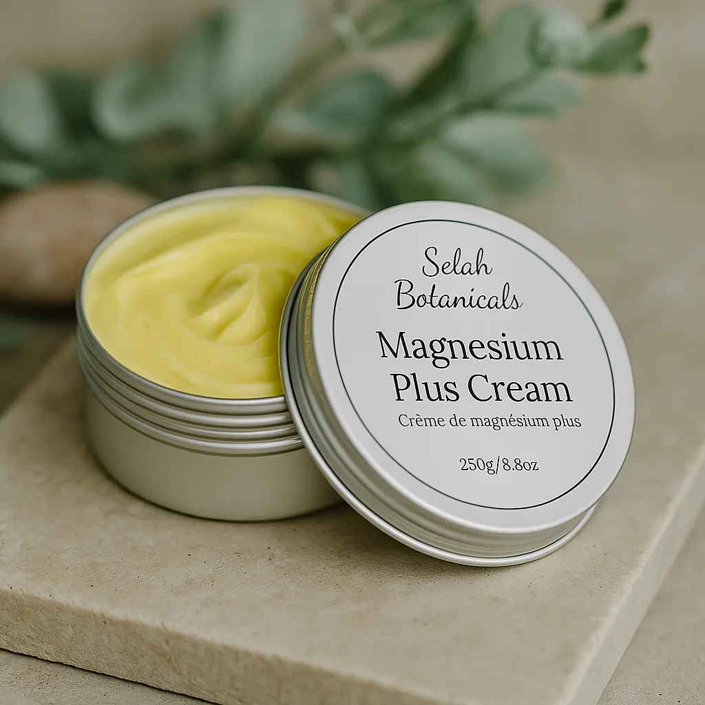 An open tin of Selah Botanicals Magnesium Plus Cream with a yellow cream inside, placed on a stone surface with green leaves in the background.
